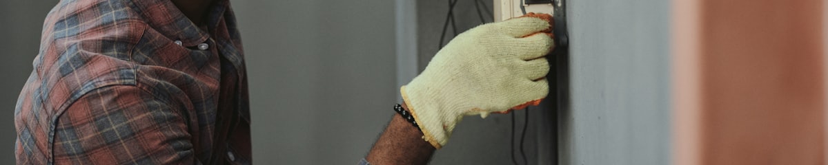 Close-up of an electrical outlet being inspected by hand